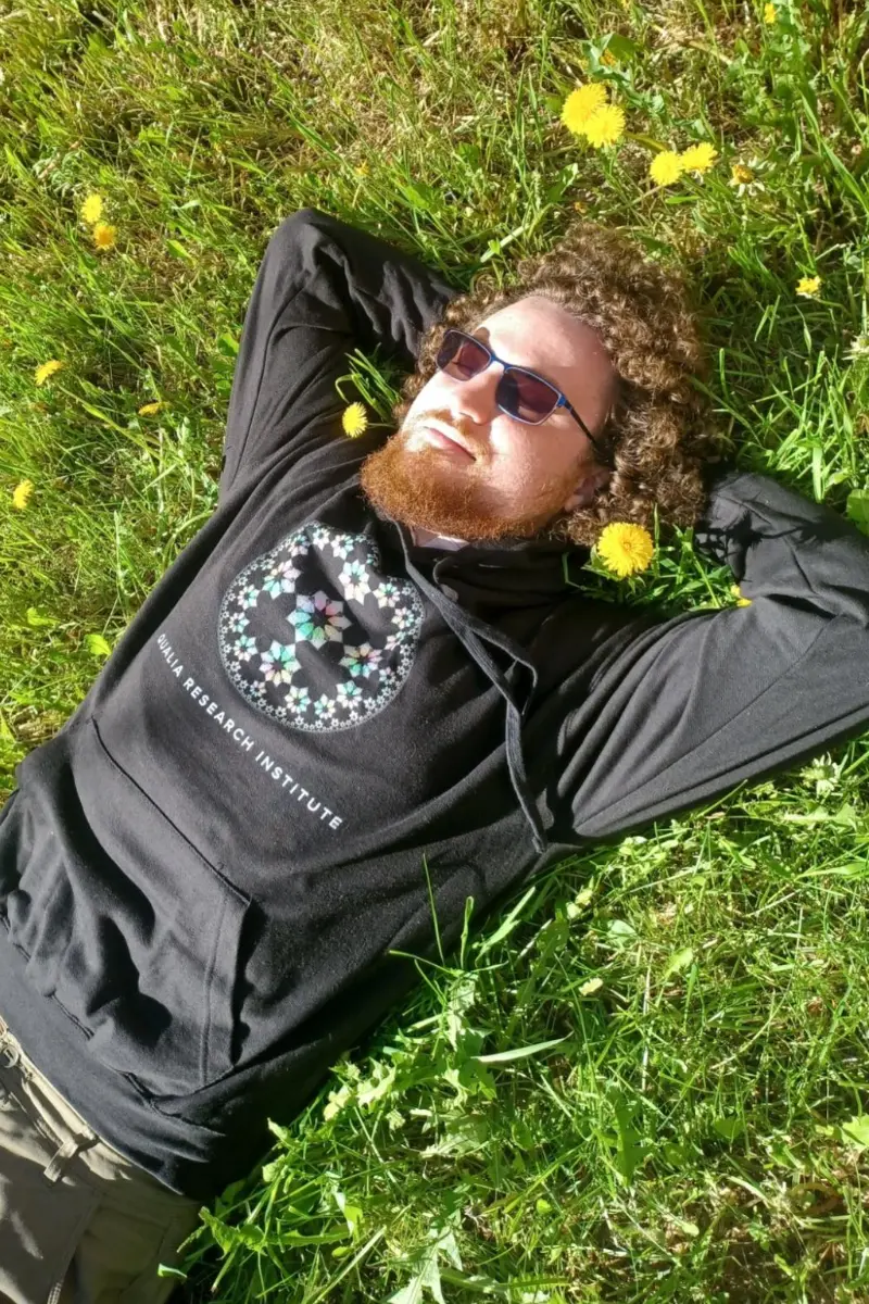 wystan lying on the grass wearing a qri hoodie